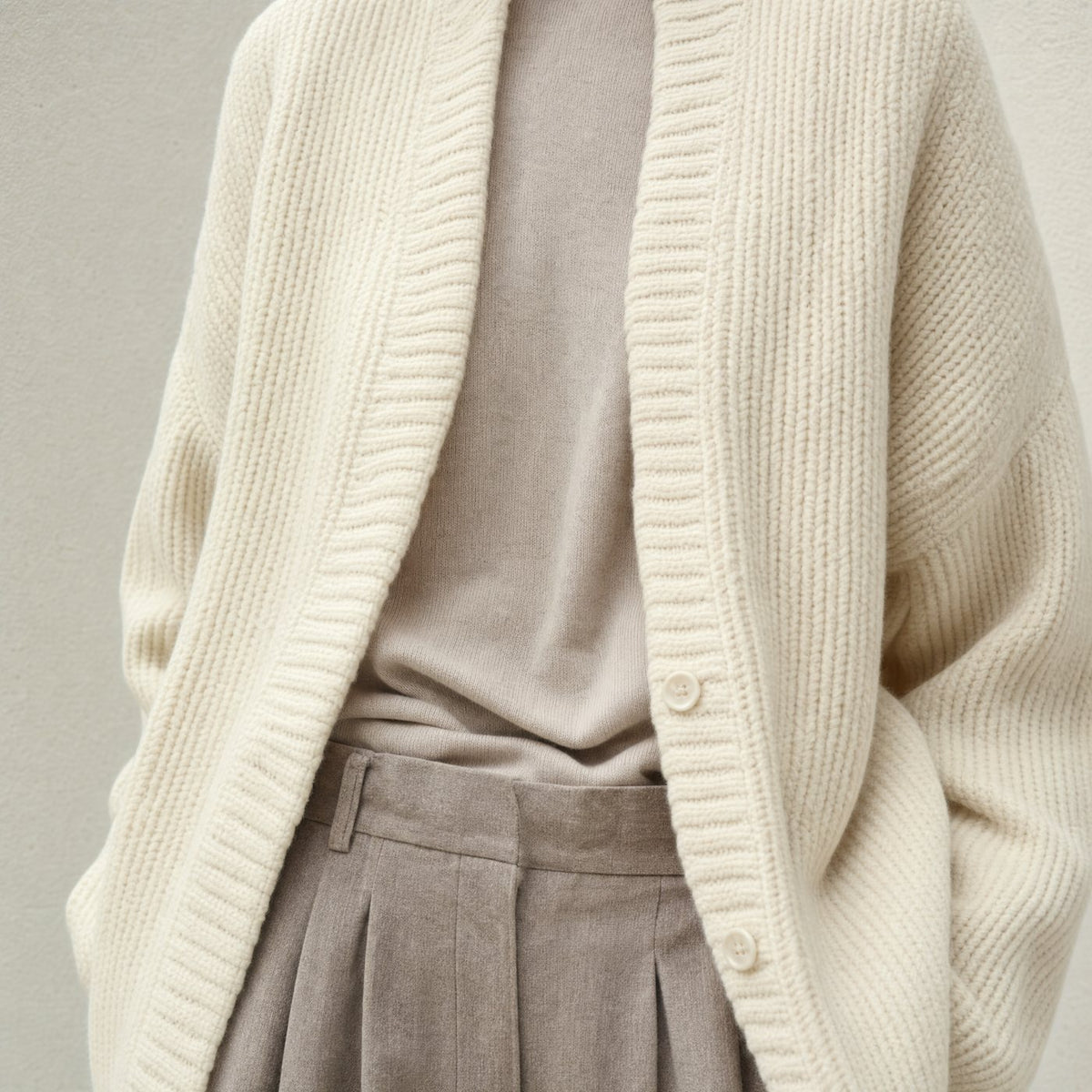 Cremefarbener Rippstrick-Cardigan über feinem Strickoberteil